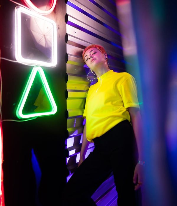 Woman in a light, energetic pose against a dark background with purple accents.